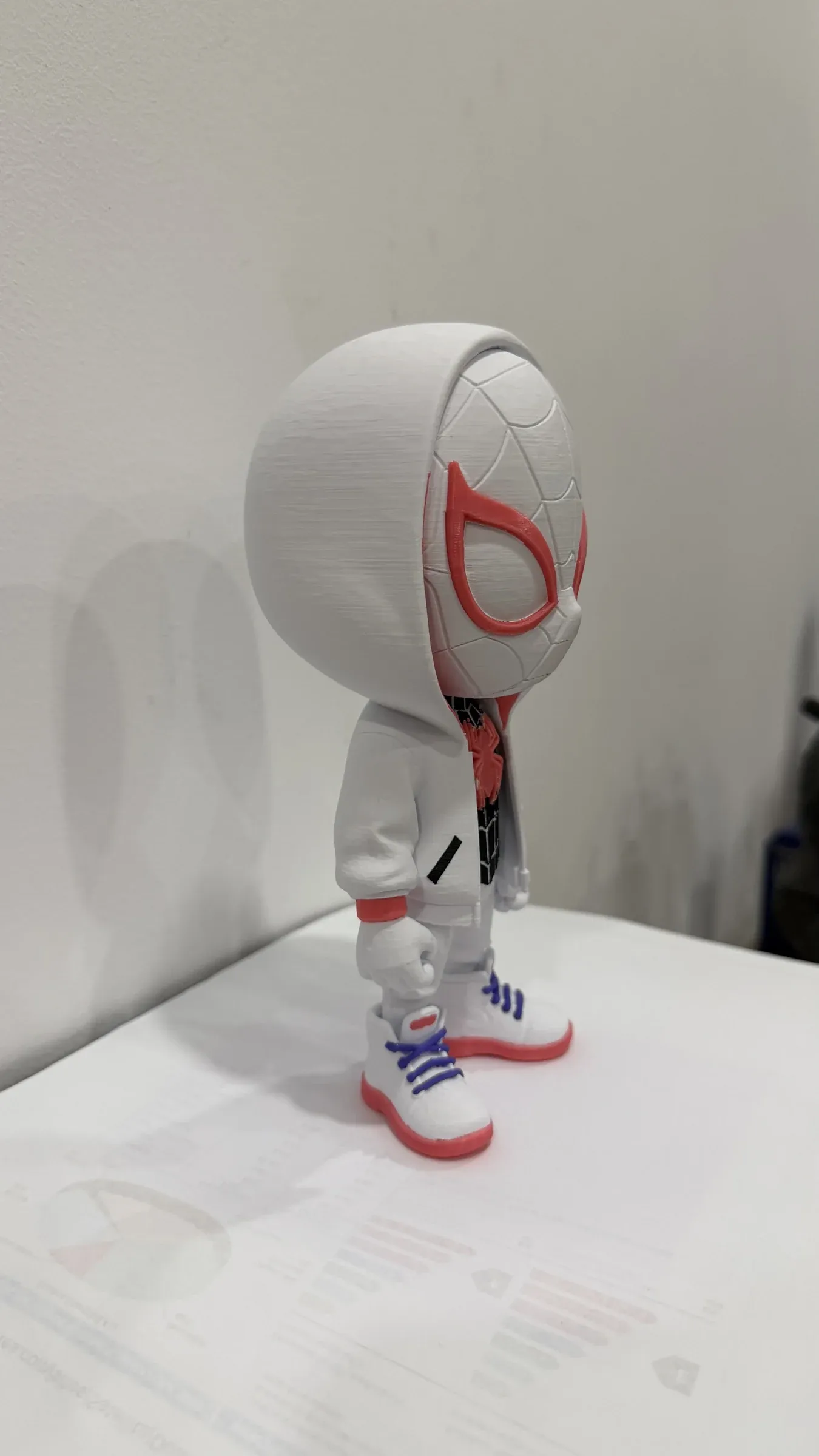 White figure in profile with a hood, red-lined eyes and white trainers with red soles.