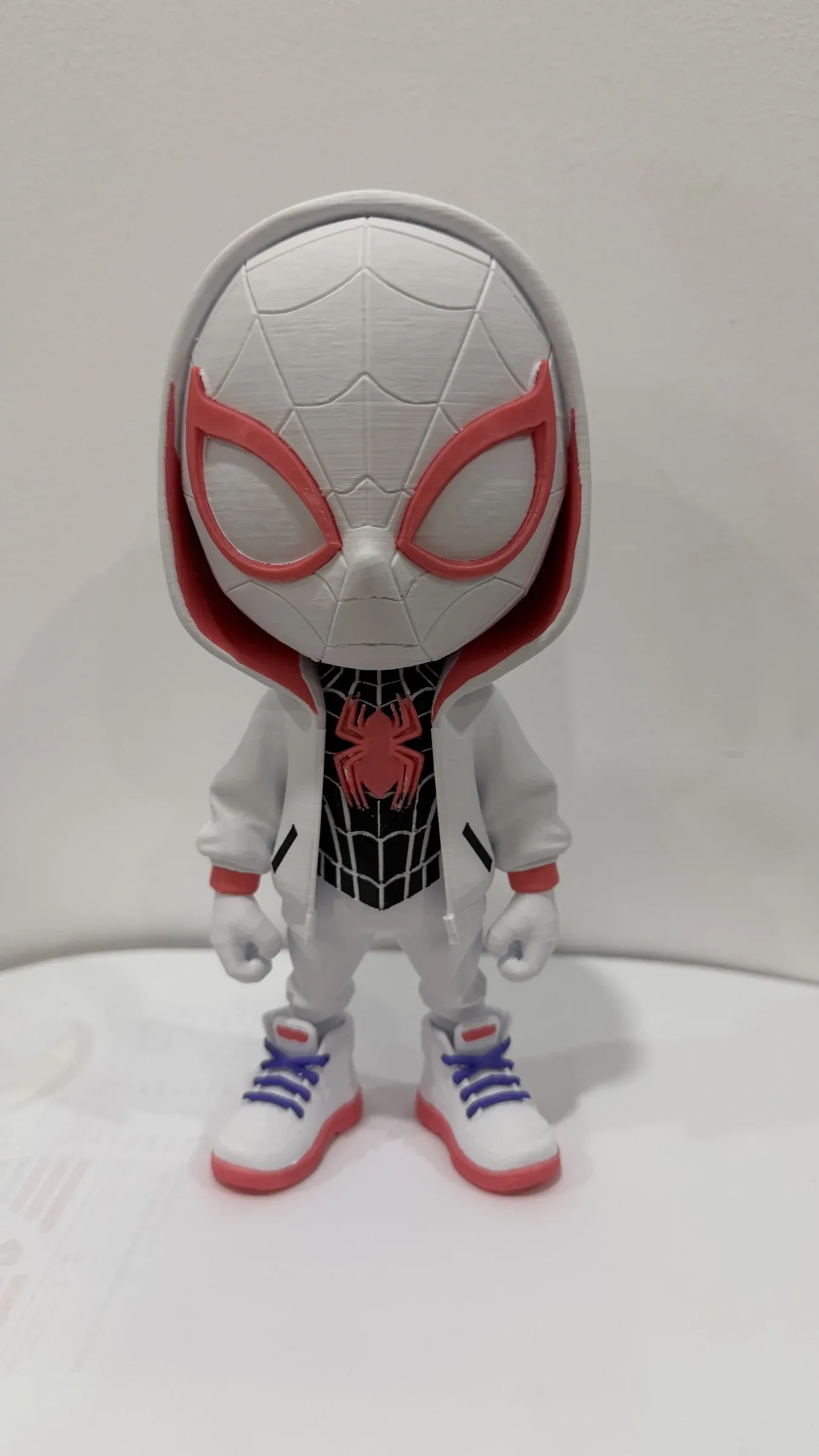 Standing chibi figure with a white head, red eyes, hooded jacket and white trousers.