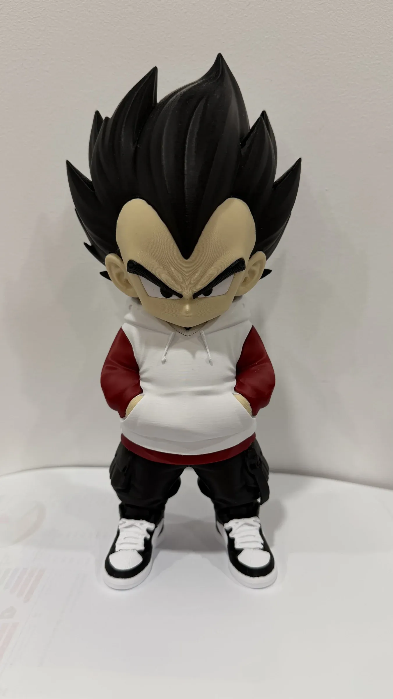 Front view of figure with white hoodie, dark red trousers and blue and white trainers