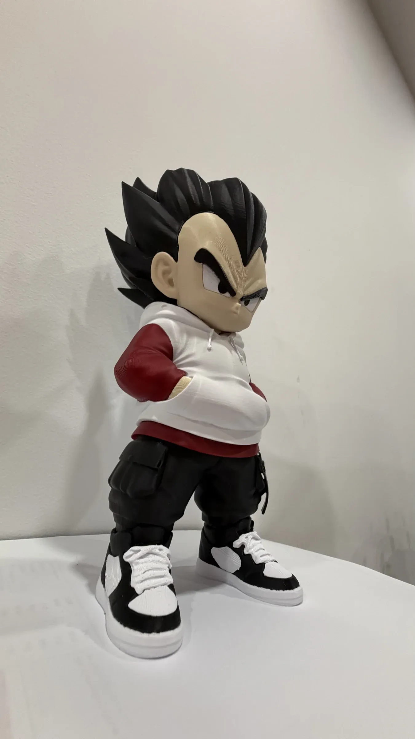 Figure of a boy with arms folded and a serious face, standing on a white surface