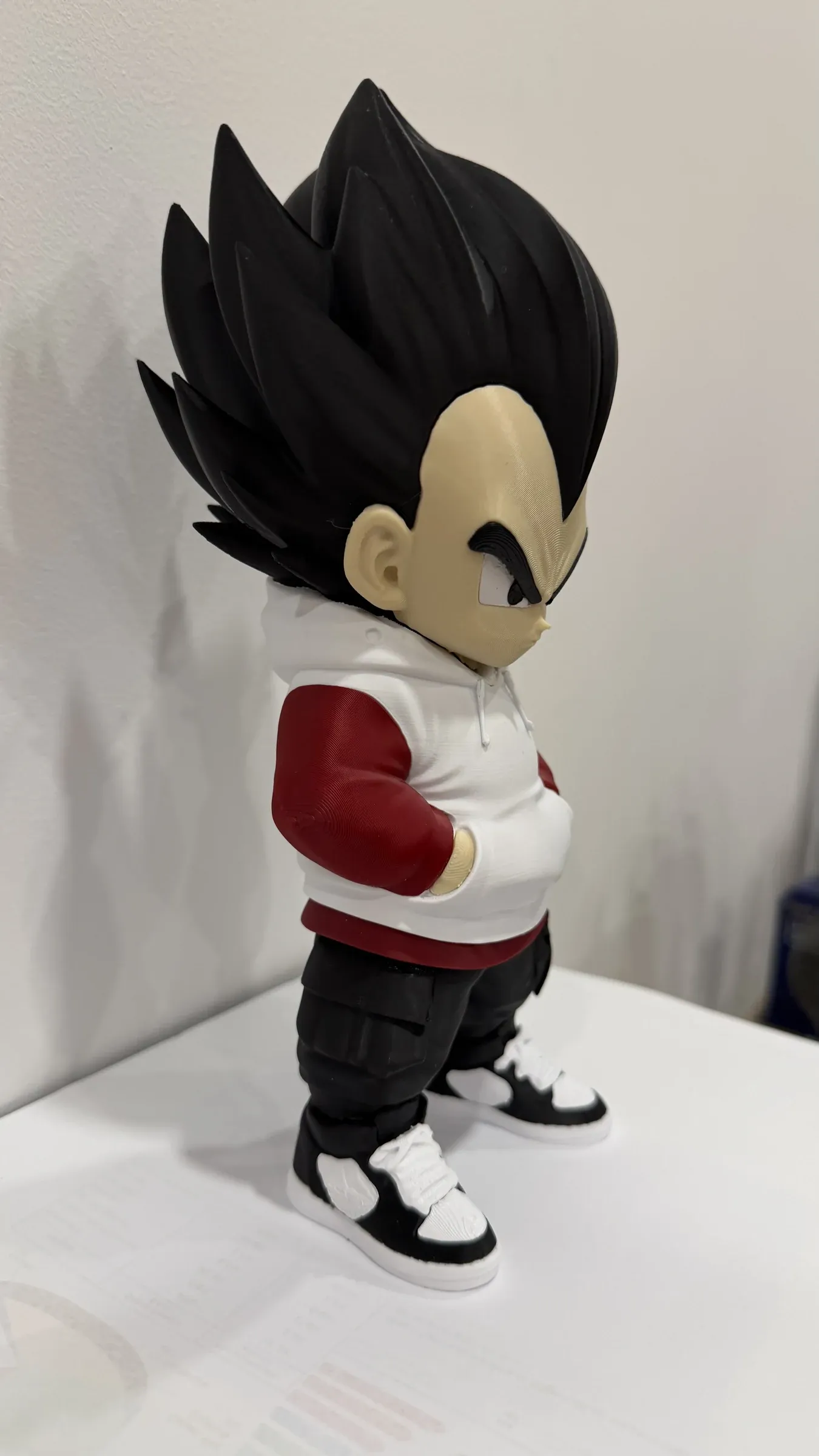 Side view of figure with large head, spiky black hair and white hoodie