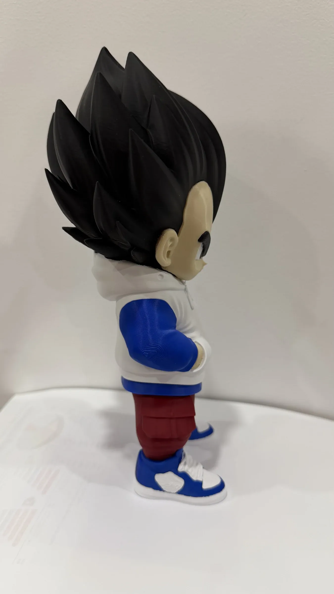 Side view of figure with spiky hair, white hoodie, red trousers and blue and white trainers