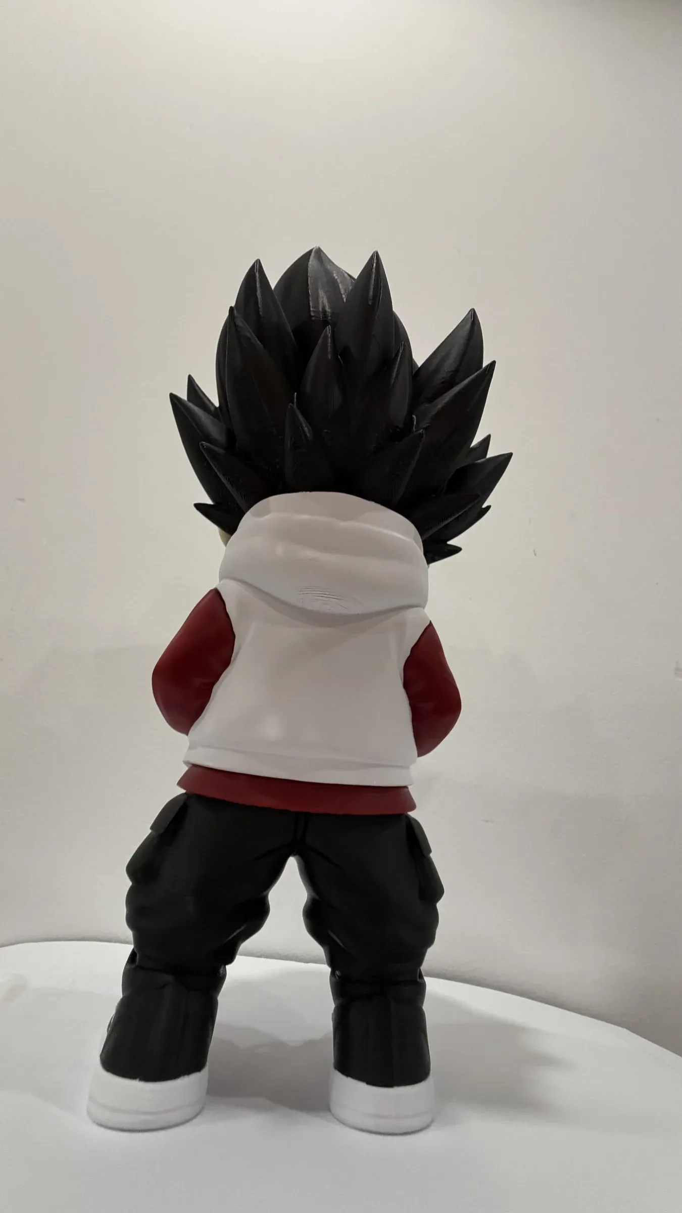 Back view of figure with spiky black hair, white hoodie and dark trousers