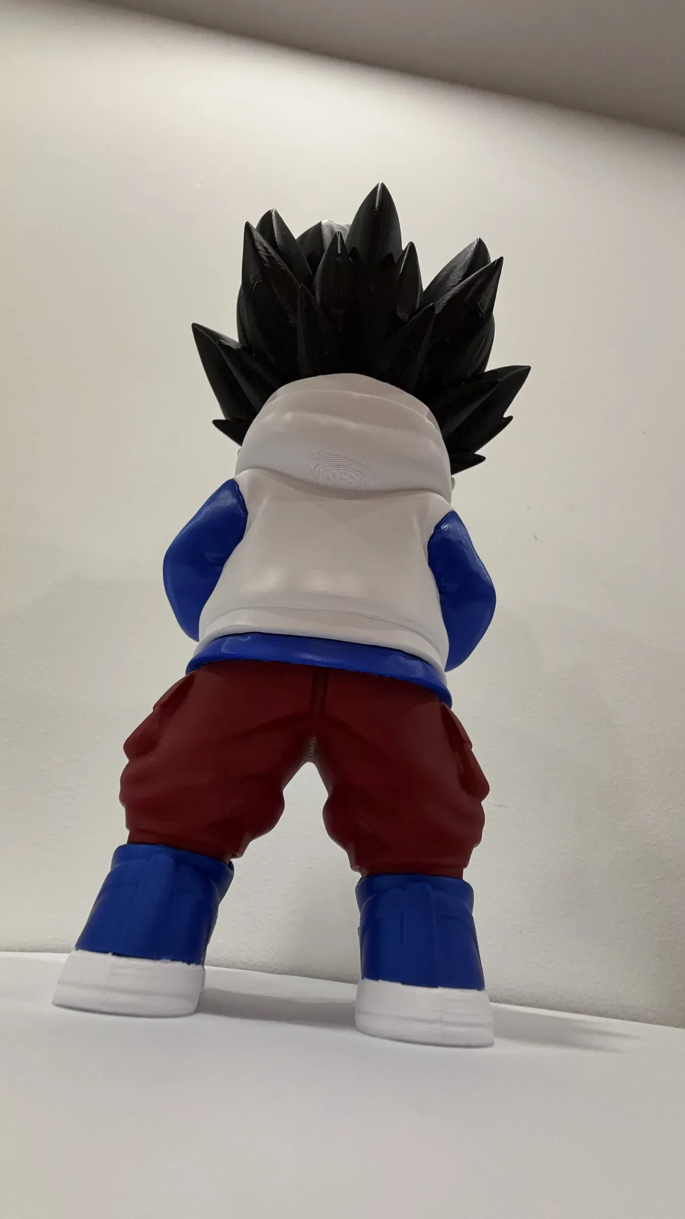 Back view of figure with spiky black hair, white hoodie and red trousers