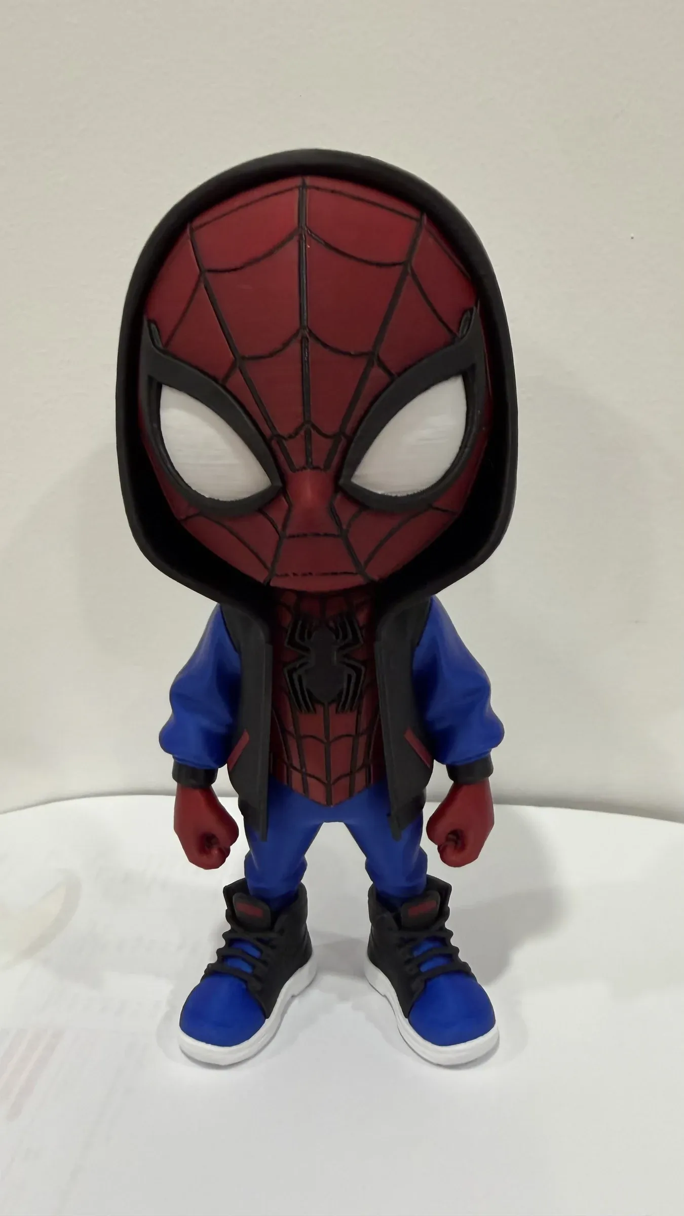 Chibi figure standing with arms at its sides, blue jacket and black and blue trainers with white soles